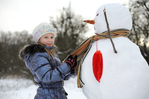 An image of little girl near big snowman