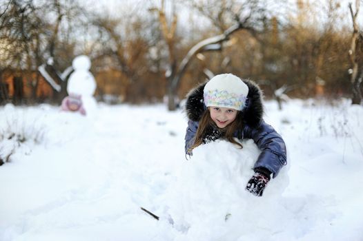 Little Girl rolling snow to make snowman