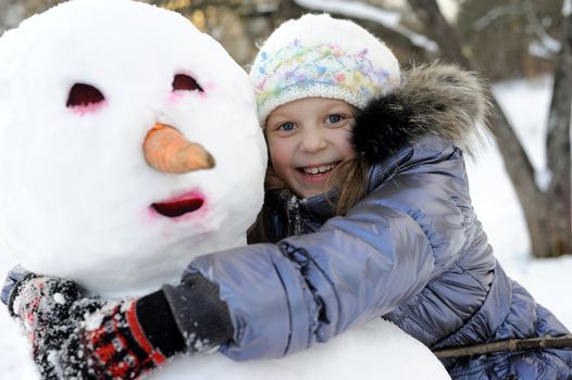 An portraits of happy little girl posing with snowman