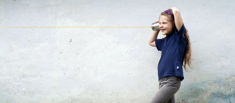 A girl playing with a toy-telephone outdoors