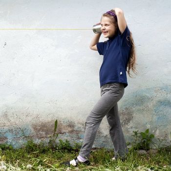 An image of a girl  with a toy-telephone outdoors