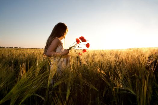 An image of a girl in the field of barley at sunset