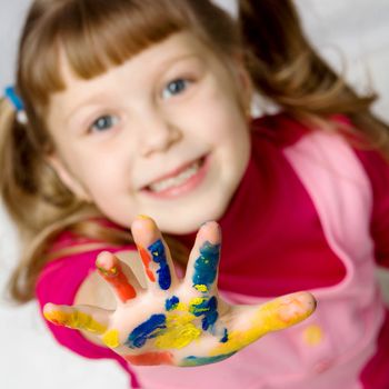 An image of a little girl with her hand in paint