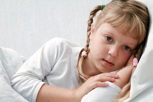 An ill girl on a bed under cover