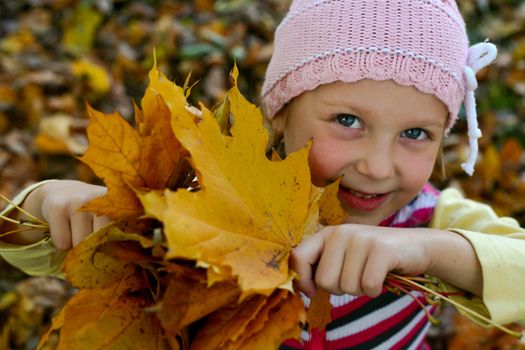 A little girl keeping yellow leaves in her hands