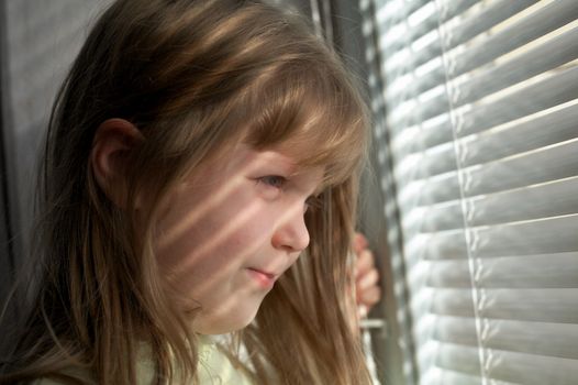 A girl is looking in the window with jalousie