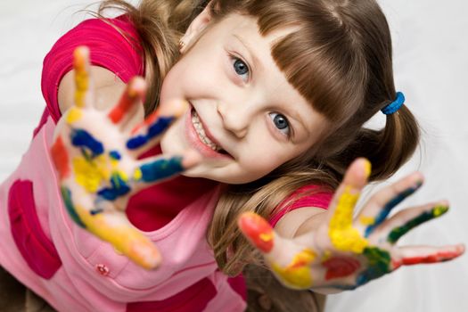 An image of a little girl with her hands in paint