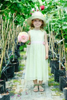 An image of a little beautiful girl in a greenhouse