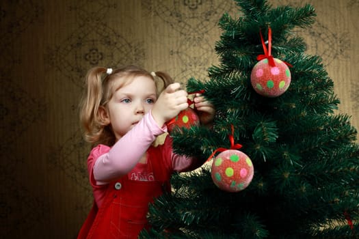 A little girl decorating a new year tree with balls
