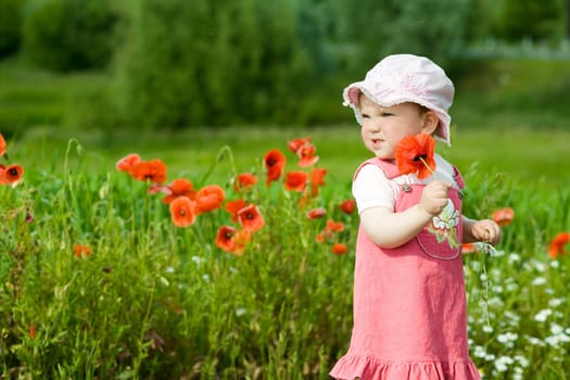 An image of baby-girl amongst green field with red poppies