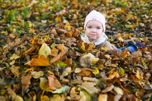 A little child playing in yellow maple leaves