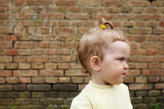 An image of baby near a yellow brick wall