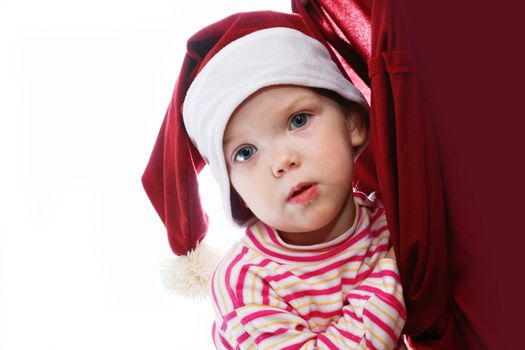An image of happiness baby in red hat looking into christmas bag