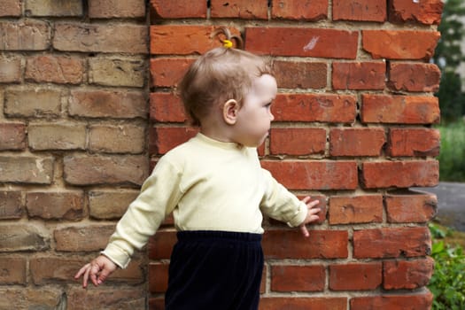 An image of  little girl near a brick wall