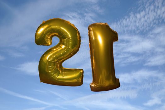 gold helium filled 21st birthday balloons floating in the sky