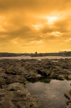 strange rock formations on the beach in ballybunion county kerry ireland with town and castle in background at sunset