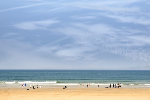 sandy golden beach with surfers and children running into the sea to surf in ballybunion county Kerry Ireland