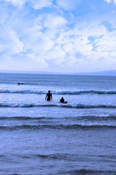 silhouette of surfers walking from the sea to the beach just before a storm