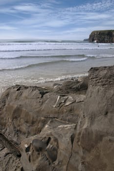 beautiful clean atlantic ocean with surfers catching the waves with cliffs in foreground on Irelands coast