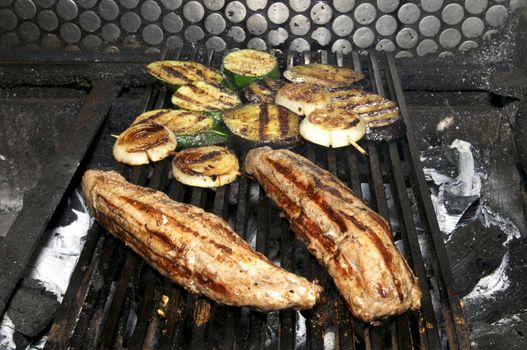 Cooking meat on the grill with vegetables