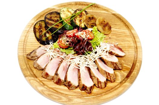 grilled meat with vegetables and herbs on a wooden plate