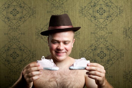 An image of a young man with little shoes in his arms