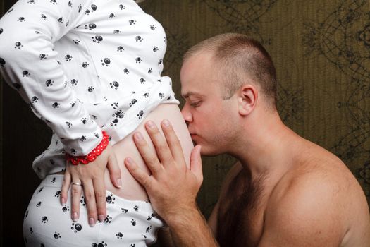 An image of a man kissing his wife's abdomen