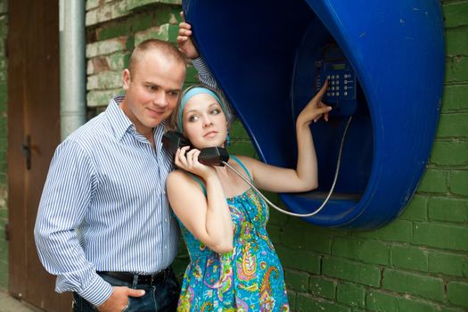 An image of a young couple at telephone in the street
