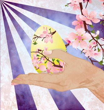 hand with easter egg decorated with pink tree flowers on grunge background