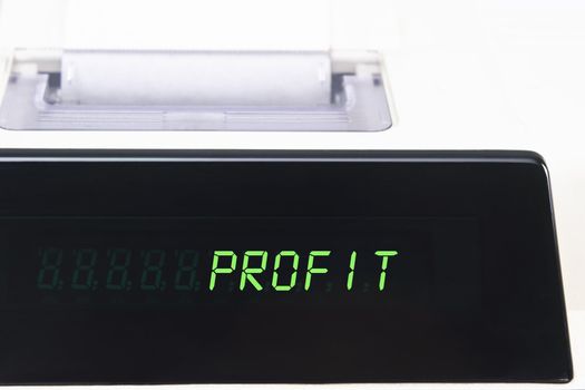 Close up of a calculator screen showing the word profit in bright green simulated LED.  Paper roll is visible in soft focus background.