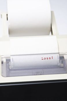 Close up of a calculator's ink roll, printing out the word 'Loss' in red.