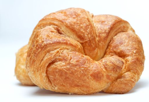 Close up of a croissant with a second croissant in soft focus behind. 