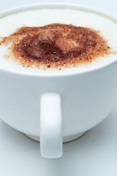 Close up of a cup of coffee with frothed milk and cocoa sprinkles, with cup handle facing front.