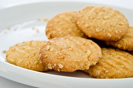 Crumbly oat biscuits (cookies) on a white china plate with crumbs visible.