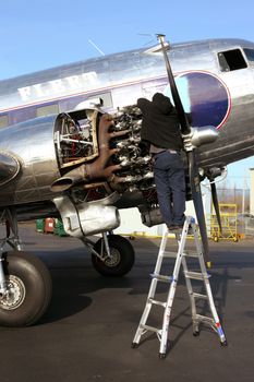An aircraft technician doing repairs on a DC3 engine.