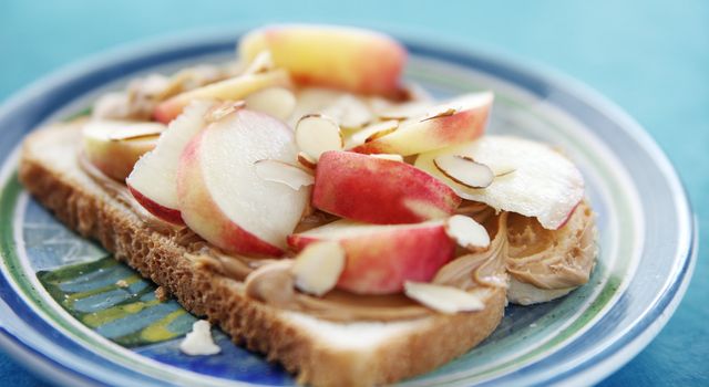 open-faced sandwich with peanut butter, fresh white peach slices and sliced almonds