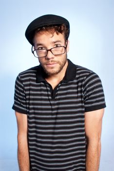 Young man modern nerd with hat and glasses wide angle portrait on blue background