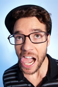 Young man modern nerd with hat and glasses wide angle close up portrait on blue background