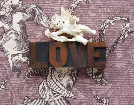 a cupid figure atop the word love in wood type