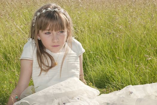 girl wearing first communion dress in the meadow