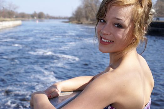 A smiling young adult happily enjoys the outdoors near the river.