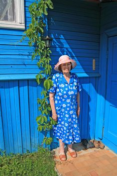 aging woman in hat on porch of the rural wooden building
