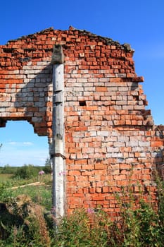 red brick destroyed building amongst green herb