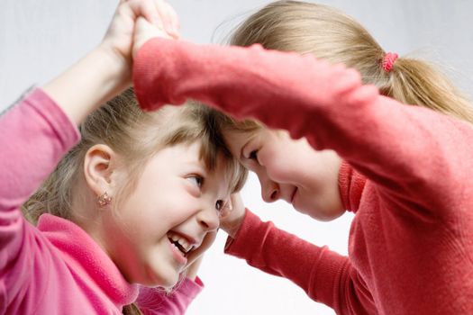 Two smiling little  girlfriends playing  with each other 