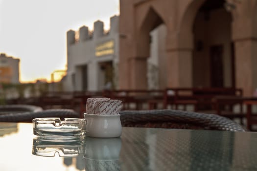 A sugar bowl and ashtray on a glass topped coffee table at the souk are ready for late afternoon visitors