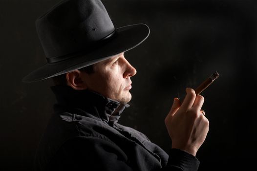 An image of a man smoking cigar in dark room