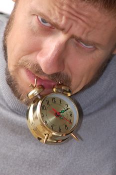 A businessman keeping an alarm clock in his teeth