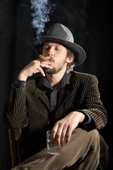An image of a smoking man with cigar and glass