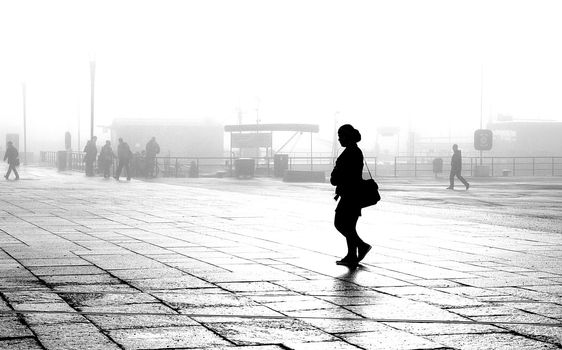 Silhouette of woman walking in foggy morning