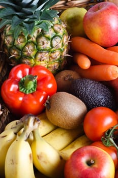 Overhead shot of a selection of fresh fruit and vegetables in a wicker basket.  Portrait orientation.